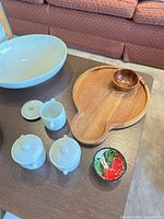All items displayed on table including glass bowl, white ceramic pieces, wooden board and bowls, painted bowl