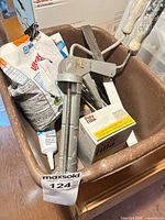 Top view of tub showing caulking gun, mixing paddles, Polyfilla box, caulk tube, bag of patching compound