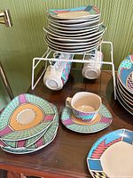 Stacked dinner and side plates, cups hanging below rack