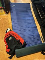 Sleeping pad unrolled with backpack placed on top showing both items