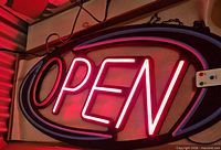 LED OPEN sign illuminated red/pink with remote visible