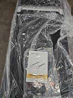 Treadmill deck wrapped in plastic with user manual and accessories visible on top