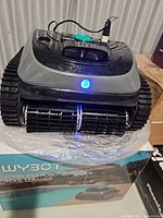 Top view of WYBOT C1 robotic pool cleaner showing body, handle, tracks, power port, and blue LED