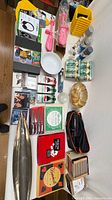 Overview of entire lot on table showing decor pieces, knives, CDs, automotive cans, hand pumps, bowl, bag