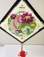 Front view of framed Chinese paper-cut art featuring koi fish and lotus with red knot tassel