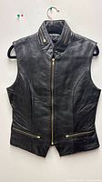 Front view of black leather vest showing zipper closure, pockets and collar detail