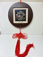 Front view of framed dragon embroidery with red knot and tassel