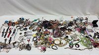 Wide view of entire assorted jewelry and watch lot spread on table