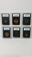 Front view of all six INB-slabbed coins