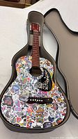 Full guitar in open case showing sticker-covered body