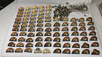 Overall view of large quantity of rainbow city lapel pins and bag of clutches