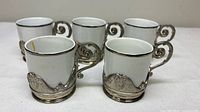Front view of all five espresso cups showing ornate holders and porcelain liners