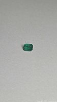 Front view of octagon-cut green emerald on neutral background