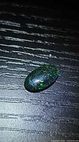 Front view of oval cabochon black opal showing pinfire play-of-colour