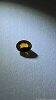 Oval faceted bi-colored sapphire on textured background