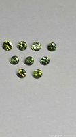 Eight round green sapphires arranged on neutral background