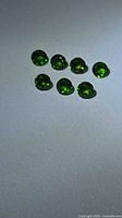 Seven round green gemstones on light surface