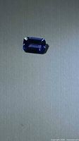 Emerald-cut deep blue Tanzanite against neutral background
