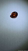 Loose oval burnt orange gemstone on neutral background