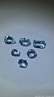 Six aquamarine gemstones grouped together showing various facets and cuts