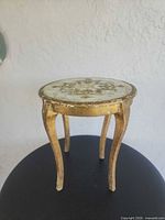 Full view of small round wooden accent table on black surface