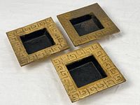 three square gold-tone cast iron ashtrays