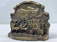 Front view showing entire brass bookend with stagecoach relief