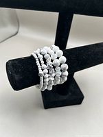 Stack of six white howlite and crystal bead stretch bracelets on display bar