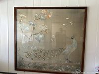 Full view of framed embroidered silk panel on wall
