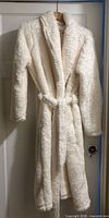 Full view of cream sherpa plush robe hanging with belt