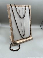 neck form displaying long bead necklace, shorter pendant necklace, and bracelet in front
