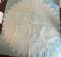 Full view of circular lace textile laid flat