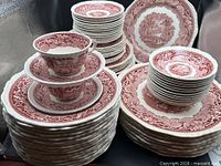 Stacked dinnerware showing plates, cups, bowls in Vista Pink pattern
