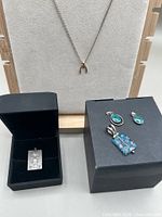 Group shot showing necklace on stand, Taxco pendant in box, Murano and chrysocolla pendants on box