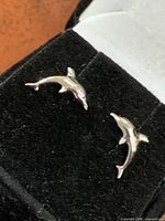 Front view of both sterling silver dolphin studs on display pad