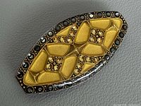Front view of gold-tone marquise brooch with black and amber crystals