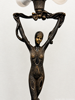 Close view of bronze female figure showing signed stylized detailing