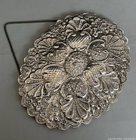 Front view showing full ornate oval silver mirror with detailed repousse pattern