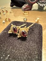 Pair of gold earrings with red cabochon garnets on display pad