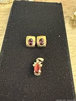 Earrings and pendant on black surface showing size and design