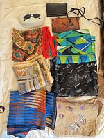 Full lot showing scarves, wallet, purses, sunglasses case, pendant necklace