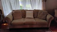 Front view of beige 3-seater sofa with cushions and pillows