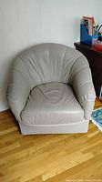 front view of beige leather barrel armchair showing seat and armrests