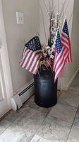 black metal milk can with faux flowers and flags, full view