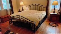 Full view of assembled queen black metal bed with mattress showing curved headboard and footboard