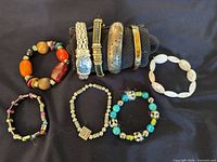 Group shot showing nine bracelets including four metal bangles on display form, four stretch bead bracelets and one white slip-on bangle