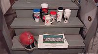 overall lot on steps showing helmet, drinkware and stack of prints