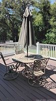 Round cast aluminum table, swivel chairs, umbrella on deck