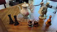 All items displayed on table: teapot, figurine, candlesticks, three visible nesting dolls, ceramic bell