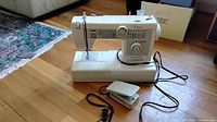 Front view of sewing machine with foot pedal and cords